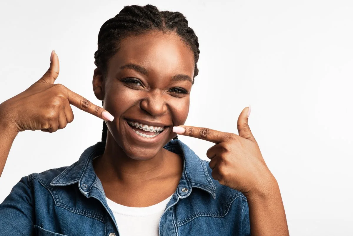 Teenage patient smiling and pointing to her Fastbraces® braces